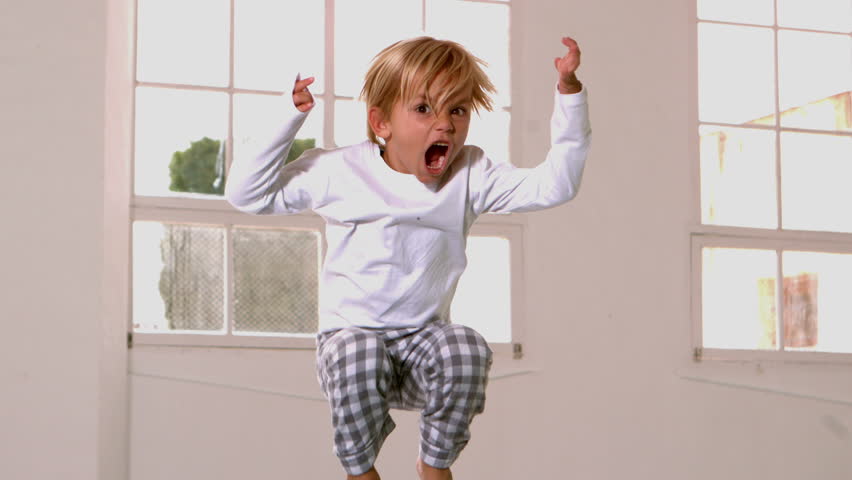 Boy in pajamas jumping and yelling in front of window in slow motion