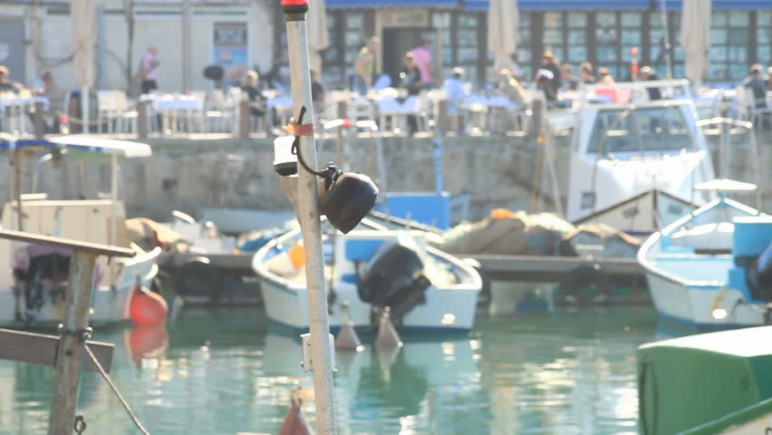 long shot of boats anchored at Jaffa port with people in the back seen out of focus