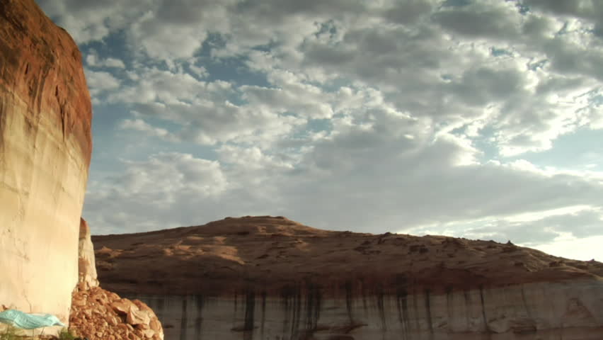 tilt down shot from red rock cliffs to houseboat on Lake Powell