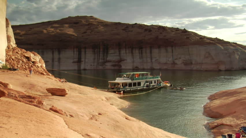 houseboat moored to red rock in Lake Powell Canyon