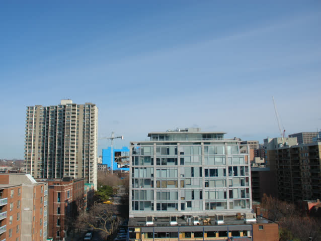 Time lapse of condo, flanked by 2 construction cranes. Clouds float by.