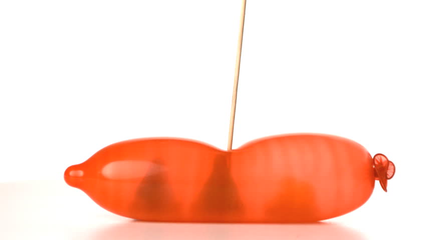 Cocktail stick popping blown up condom with revealing three condoms in slow motion