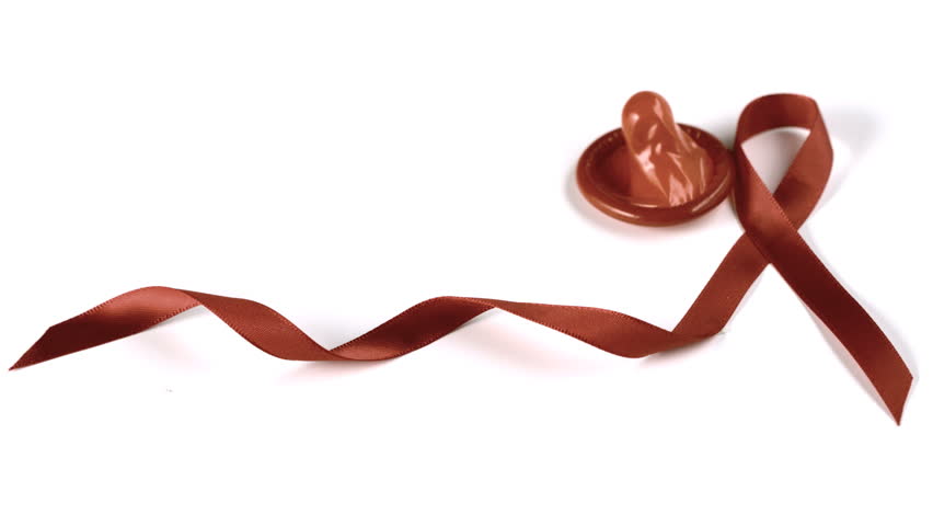 Condom falling over beside Aids red ribbon symbol in slow motion