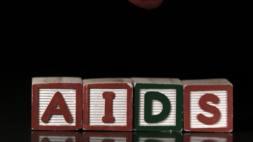 Coloured condoms falling on blocks spelling aids in slow motion