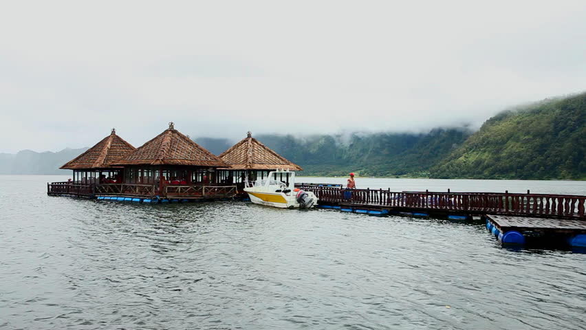 LAKE BATUR, BALI - JANUARY 21: Tourist crossing jetty to restaurant on Lake Batur on January 21, 2012 in Bali, Indonesia. Inhabitants of the lake rely on tourism and fishing for their subsistence.