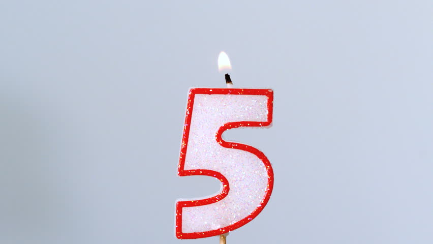 Five birthday candle flickering and extinguishing on blue background in slow motion