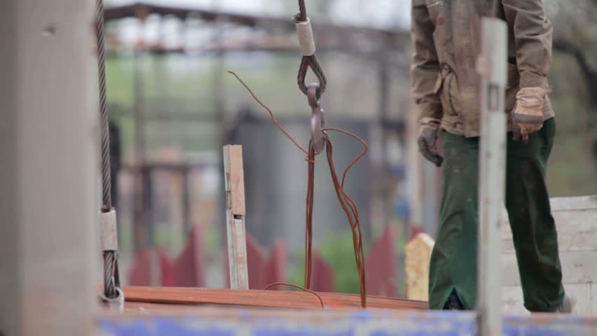 Workers at construction site unloading rebar