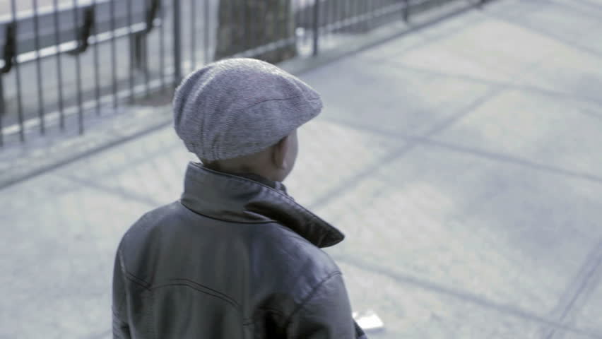 Young African American Kid walking down the street with a black coat and hat