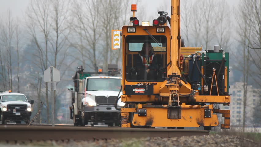 FRASER VALLEY, BRITISH COLUMBIA - MARCH 12, 2013: A railway crew rolls by, including a tie crane used for repairing railway ties in the Fraser Valley of southern British Columbia on March 12, 2013.  