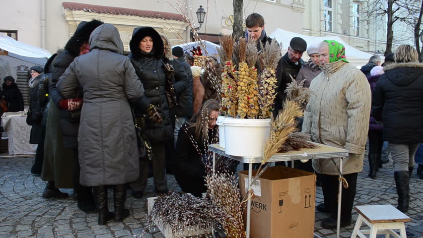 VILNIUS, LITHUANIA - MARCH 02: Old grandmother woman sell catkin plant branches and various handmade palm in outdoor spring fair market and people buy them on March 02, 2012 in Vilnius.