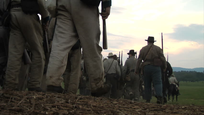CHICKAMAUGA, GEORGIA - OCTOBER 2008 - large-scale, epic Civil War anniversary reenactment -- in the middle of battle.  Confederate Army marches across field, down hill on dirt road in column as sun sets. 