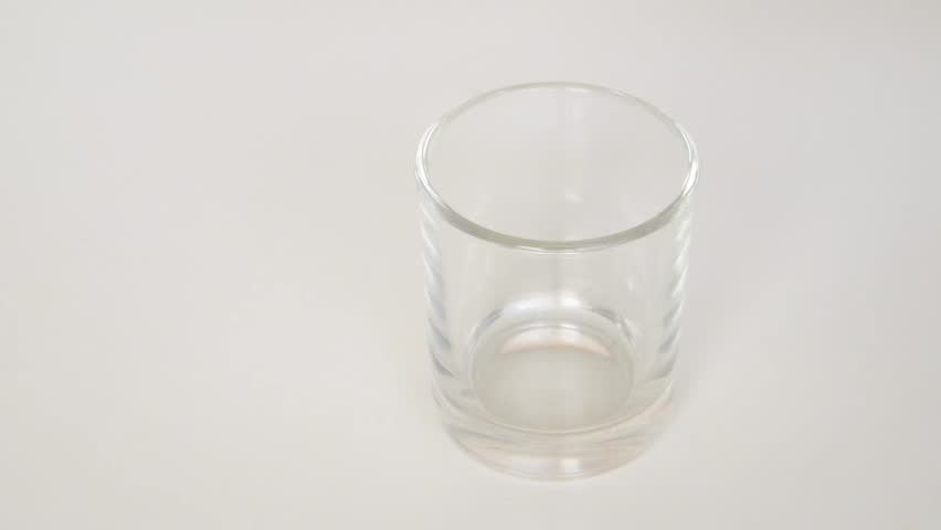 Herbal medicine capsules dropping into a glass.