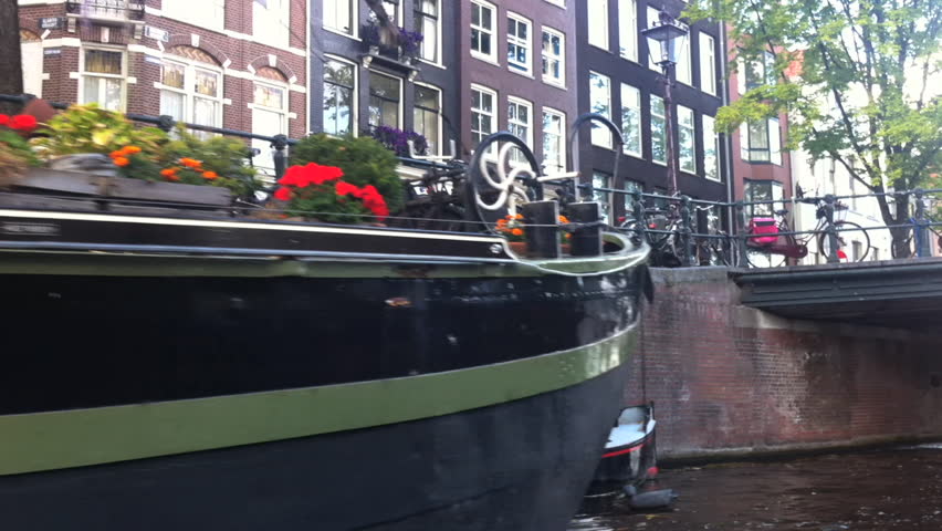 AMSTERDAM - SEPTEMBER 2012: POV from boat as it travels down canals, capturing bicycles, cars,bridges, and houseboats. The canals in Netherlands were dug in 17th century.