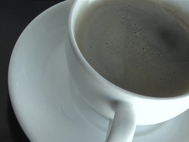 Stirring sugar into a cup of black coffee