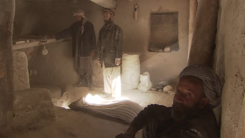 North-east of Fayzabad, Afghanistan - November 12, 2010:  Tree men working in a water powered mill in the mountains in the far north-east of Afghanistan.