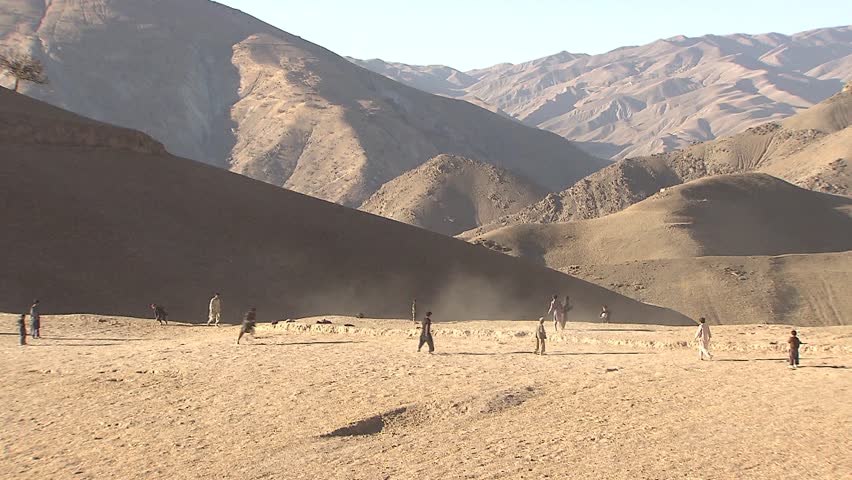 Village in Upper Yaftal, Afghanistan - November 9, 2010: Boys playing soccer/football on a small plateau near a village in north-east Afghanistan.