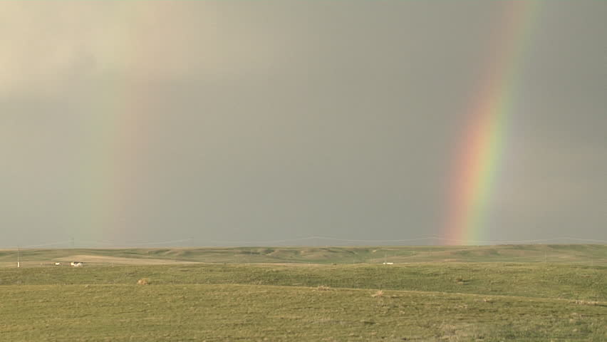 Double Rainbow. Rain falling from departing shower illuminated by sun
