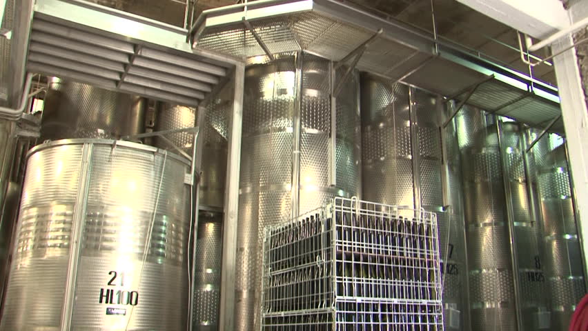 Crates of empty wine bottles and stainless steel distilling vats at a winery
