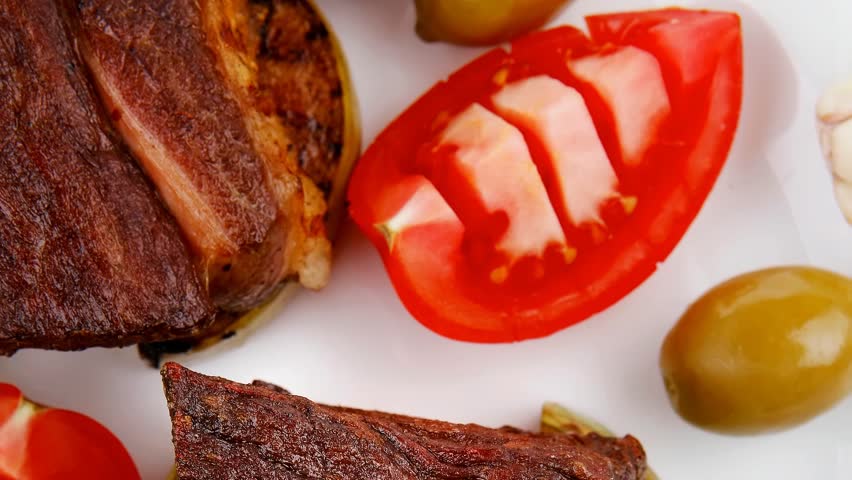 grilled meat : beef ( lamb ) garnished with tomatoes green and black olives on white plate 