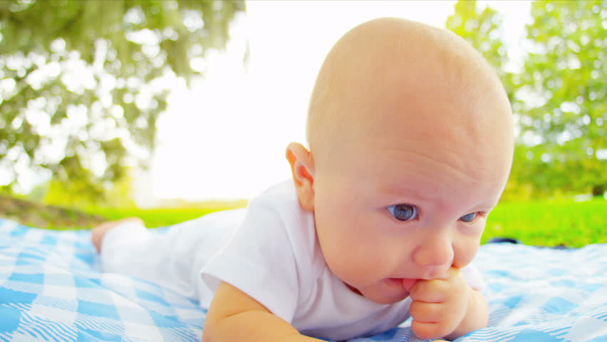 Full face happy Caucasian baby lying on picnic blanket outdoors sunshine shot on RED EPIC