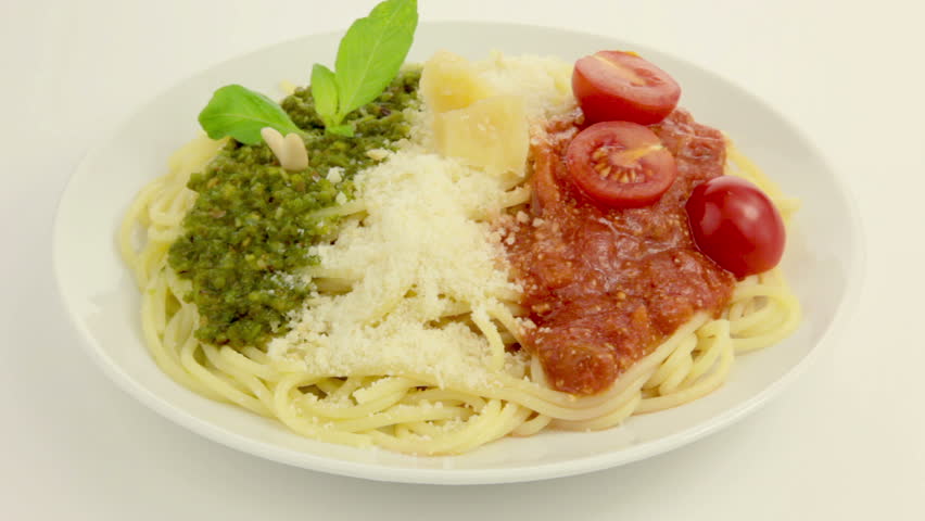On a white plate rotates pasta. On top of pasta - Pesto, Parmesan and Tomato sauce - in the national colors of the Italian flag