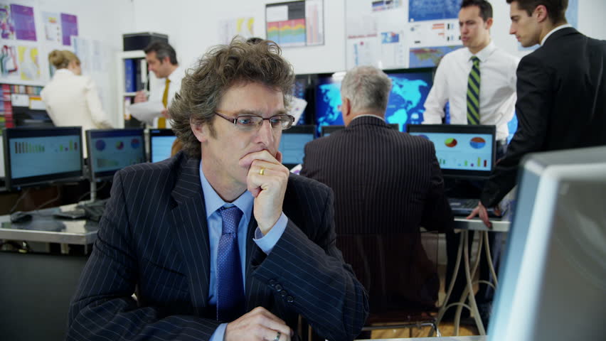 A very bored and tired mature businessman is struggling to stay awake at his desk while he is at work. As he lapses into sleep he looks around to check that his colleagues haven't noticed.