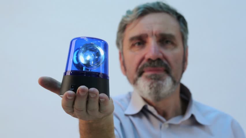 Senior man with beard holds blue blinker on hand, focus on flasher