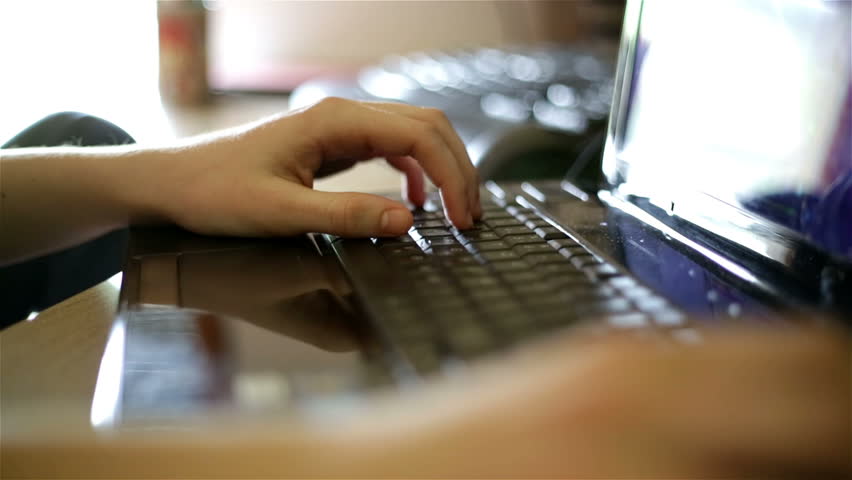 A young boy playing an online game on his personal computer. Close-up on his hands and fingers pushing the keyboard buttons.