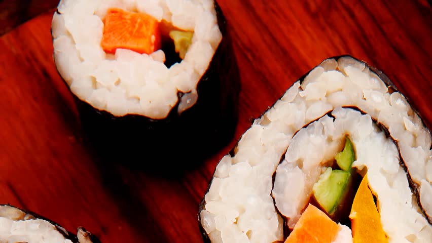 Japanese traditional Cuisine - Roll with Cucumber Cream Cheese with raw Tuna(maguro) and Salmon(sake) inside. on wooden plate with wasabi and ginger isolated over white background