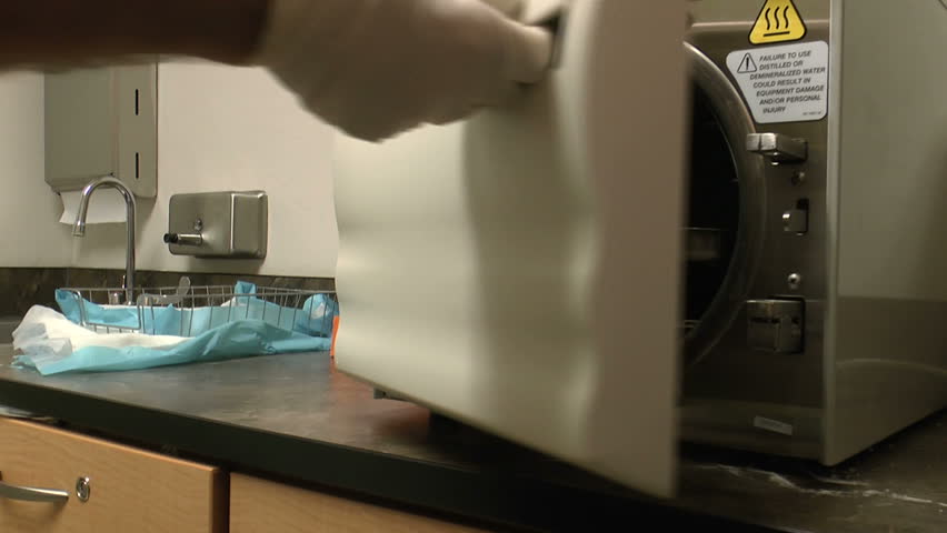 Medical worker wears gloves, opens sterilizer door, removes tray of medical, surgical instruments. 1080p