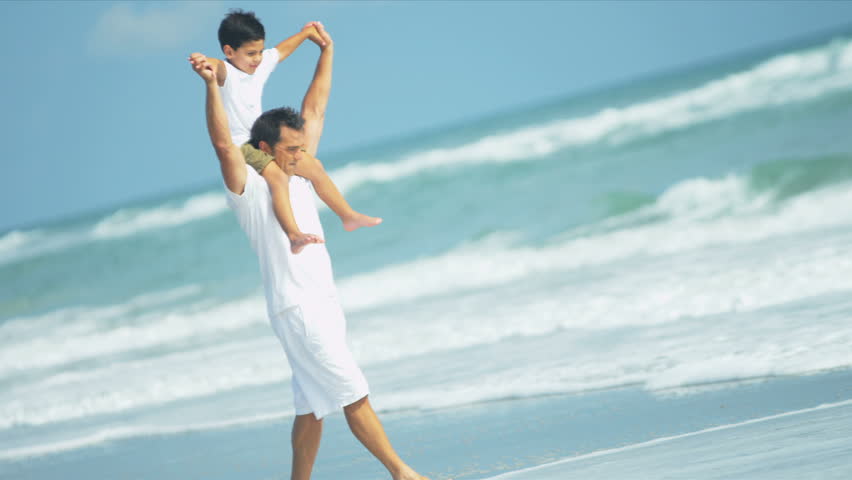 Latin American father enjoying beach with little son shot on RED EPIC