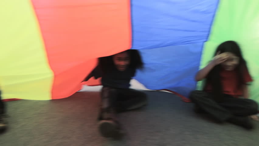 Parachute Silk - children sit and wave under a colorful parachute silk