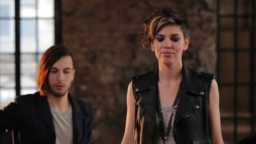 Charismatic girl singing in the studio accompanied by two guitarists