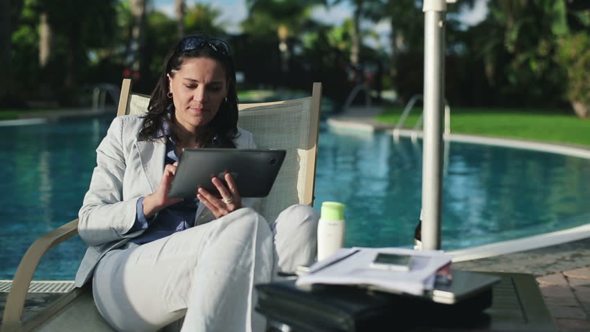 Successful businesswoman with tablet computer by the pool
