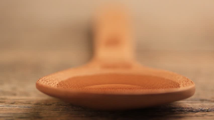 Honey pouring into wooden spoon
