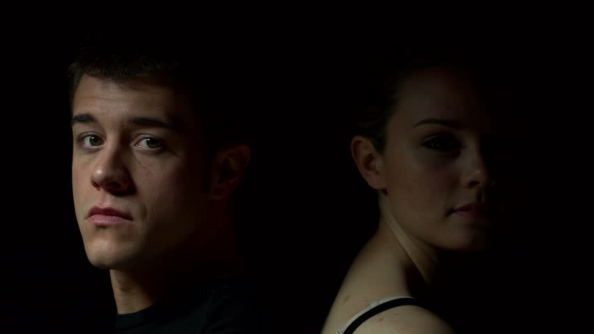 Man and woman sitting back to back in color. Experimental lighting.