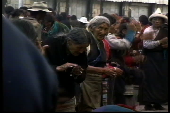 LHASA, TIBET - OCTOBER 01, 1993: Crowd of villagers bowing and praying before the juniper hearth on Barkhor Street.
