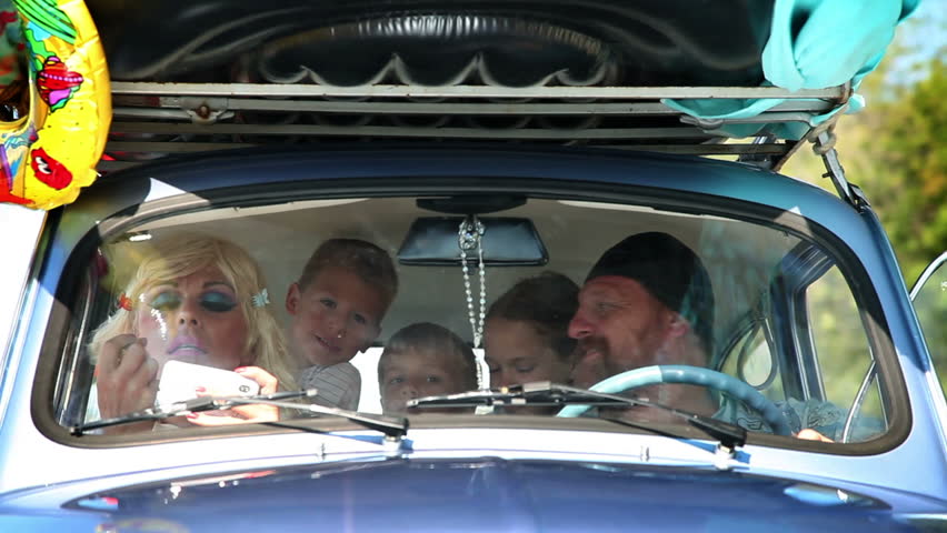 Family having fun on the road towards summer holiday in a very small car