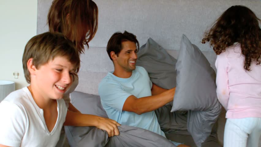 Smiling family having a pillow fight in slow motion at 250 frames per second