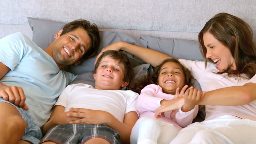 Happy family lying in a bed in slow motion at 500 frames per second