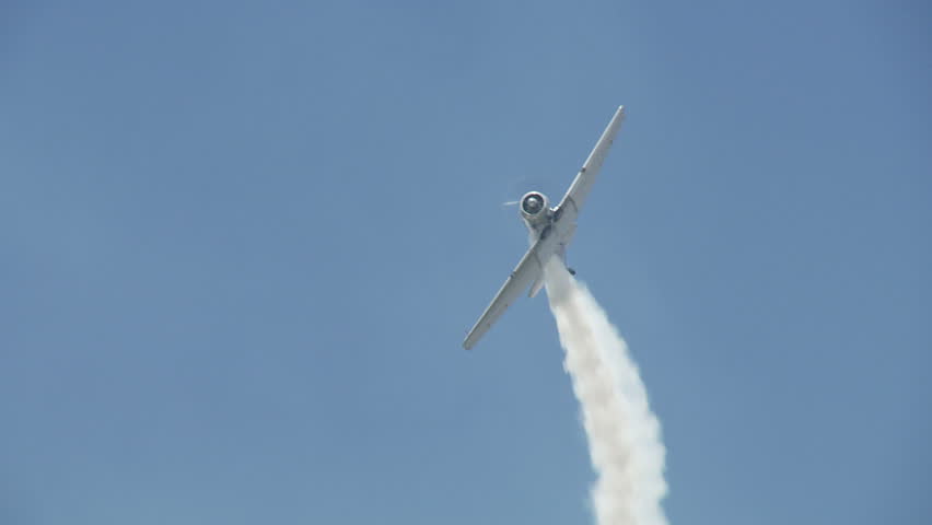US Air Force T-6 Texan training aircraft from WWII, in flight, performing stunts with smoke.