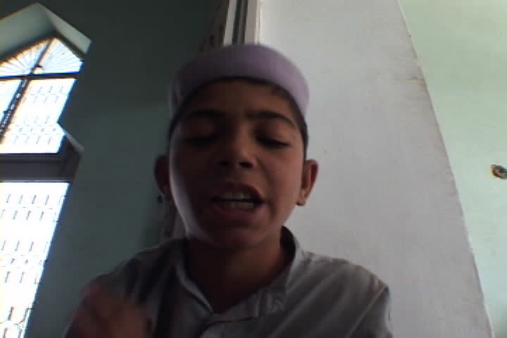 PESHAWAR, PAKISTAN - NOVEMBER 01, 2001: Young boy rocks back and forth as he recites the Koran inside the Saudi-funded Darul Uloom Junadia Ghafooria.
