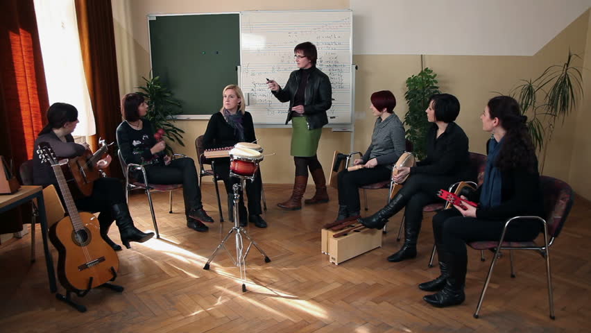 Right to left pan shot of the group of people that are learning a new song in music class 