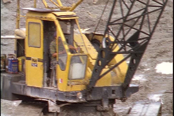 KUALA LUMPUR - OCTOBER 25, 1999: Kuala Lumpur construction site; MS construction worker operating yellow crane at construction site.