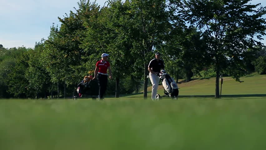 Shot of a couple that goes on the other golf course carrying all the golf equipment