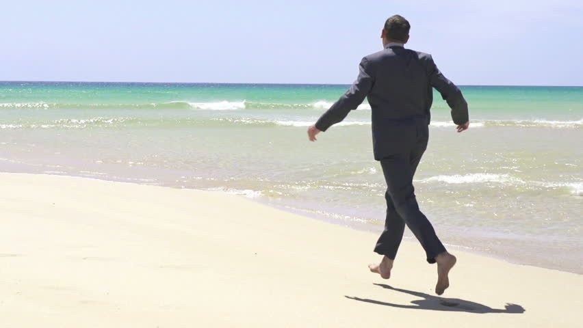 Excited businessman running on the beach
