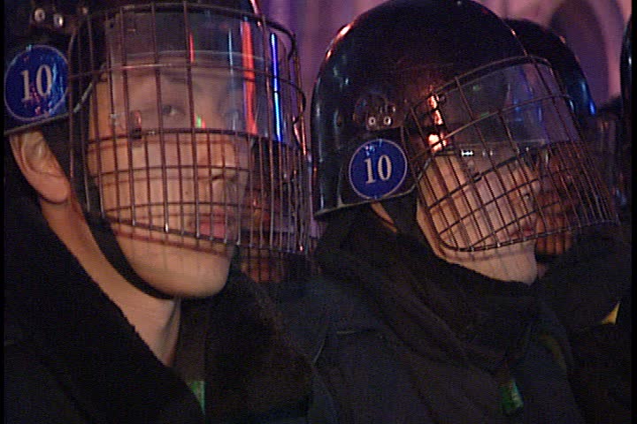 SEOUL - MARCH 02, 2003: Night time peaceful anti-war demonstration in Jung-gu; MS line of police in riot gear and helmets standing by crowd.