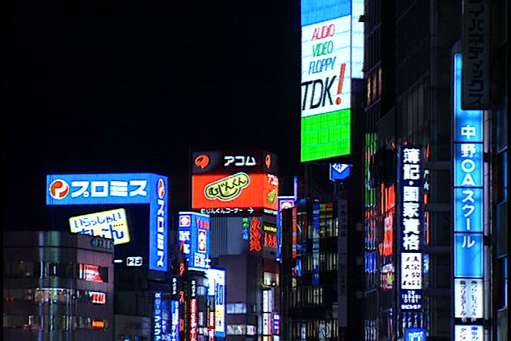 TOKYO - DECEMBER 06, 1996: MS tops of buildings in Shinjuki business district, all are covered in colorful illuminated neon and LCD signs. Camera pans from right to left across rooftops.