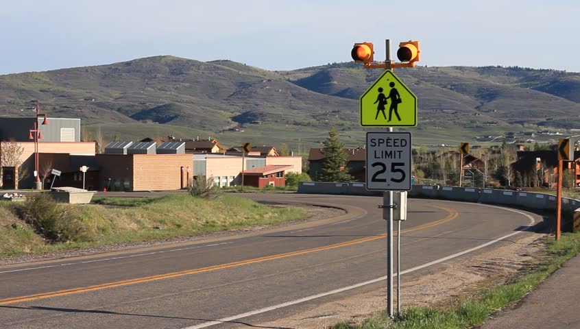 School bus passes a flashing 25 mph sign near a elementary school.