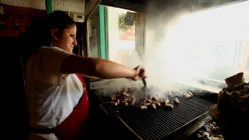 SARAJEVO, BOSNIA - AUGUST 13: Woman grilling cevapci on grill in restaurant on August 13, 2012 in Sarajevo, Bosnia. The Sarajevan Cevapi meat is famous throughout the Balkan region.